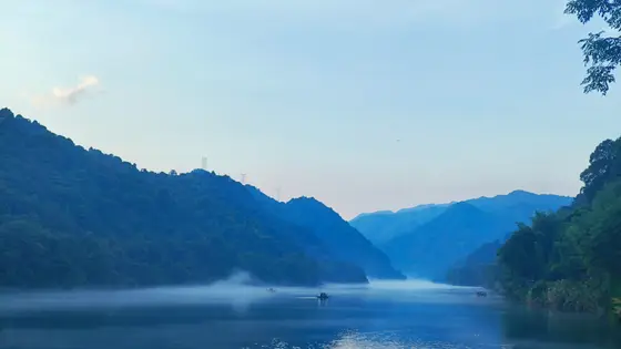 湖面如镜，倒映着青黛色的山影，薄雾轻纱般笼罩在水间。几叶扁舟悠然划过，惊起一圈圈涟漪，仿佛在低声诉说着山谷的静谧。远处的山峦层层叠叠，隐入天边的淡彩之中，宛如一幅未干的水墨画。晨曦微露，空气中弥漫着水汽的清新，让人心神宁静，恍若置身仙境。