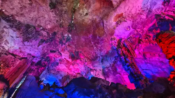 在地心的花园里，彩虹沉睡在岩壁的褶皱中。亿万年的时光与流水，雕琢出这般绚烂的梦境。光影是夜的精灵，将沉默的石笋唤醒成一片璀璨星河。