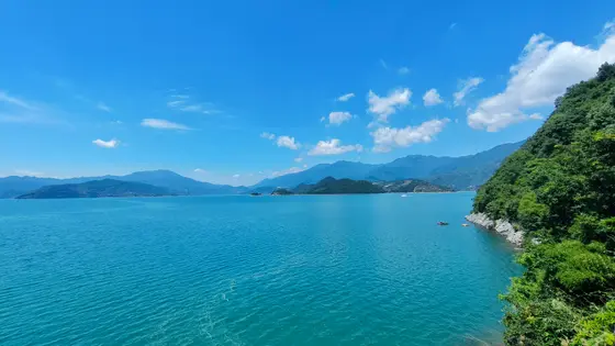 碧空如洗，几缕闲云悠然自得，倒映在如镜的湖面上。远山含黛，层层叠叠，仿佛是天地间最温柔的屏障。这一汪清蓝，静谧而深邃，藏着风的呢喃与光的低语。孤舟一点，轻轻划破水面的宁静，载着夏日的梦向远方驶去。