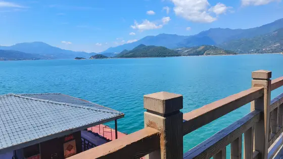 木栏轻倚，湖水如一块温润的碧玉，静静铺展在天际之下。远山含黛，似水墨晕染的屏风，将云朵的倒影细细收藏。风是透明的，拂过瓦檐的缝隙，捎来一缕关于晴空的絮语。