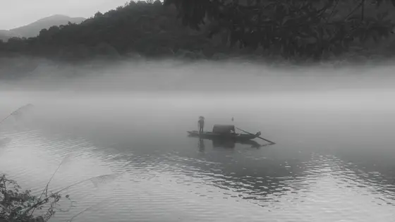 晨雾轻笼水面，如梦似幻，将远山近树都染成了一幅流动的水墨画。一叶扁舟悠然浮于湖心，船头渔人独立，仿佛与这天地融为一体。桨声轻点，搅碎一池静谧，又复归于宁静。此情此景，恍若置身于千年的诗意之中，时光在此悄然停驻。
