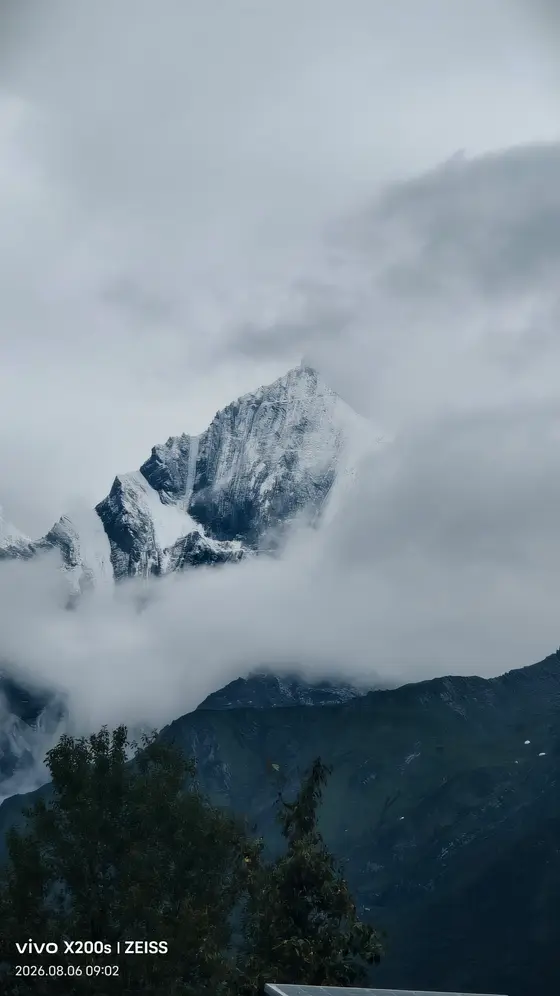 云雾轻掩峰峦,雪色与天光相融,仿佛一柄未出鞘的冰刃,静静刺入苍茫。山峦在晨霭中苏醒,每一道褶皱都藏着风与岁月的絮语。绿色的低语托起银色的沉默,世界在此刻凝成一片悠远的呼吸。