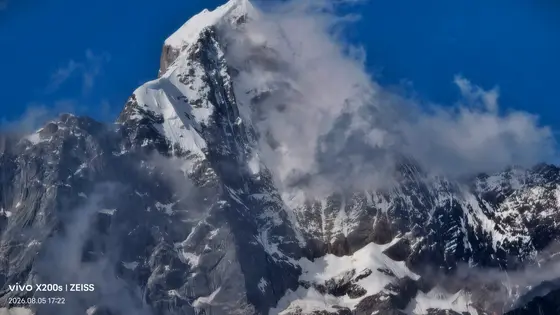 雪峰如剑,直插湛蓝天穹。云雾是它的呼吸,时而轻抚峰峦,时而缠绕山脊。白雪与深岩交错,仿佛时光在这里凝固成永恒的画卷。