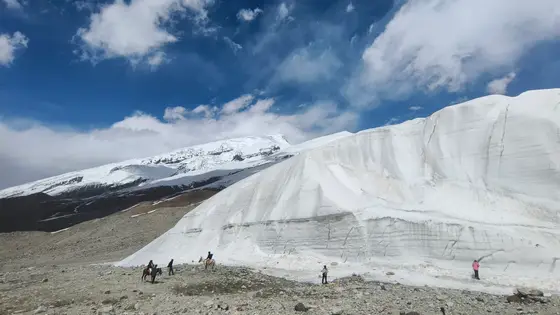 冰川是时间雕刻的白发，垂落在群山肩头。  
天空低垂，云影滑过冰壁的裂隙，像缓缓移动的古老寓言。  
碎石坡上，人马如墨点，在天地间写下细小的跋涉。  
冰舌静默流淌，却刻满千年风雪的年轮。  
此刻万物屏息，只剩光在雪面上行走，风在冰川深处低语。