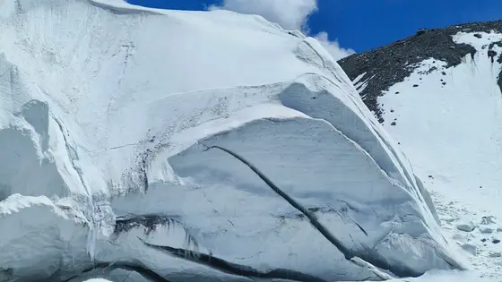 雪山静卧如沉睡的巨神，银袍裹着亿万年的寒梦。冰川裂隙是大地深刻的纹路，流淌着亘古未融的蓝。天穹低垂，云絮轻拂过刃脊，为这纯白世界染上一笔流动的温柔。