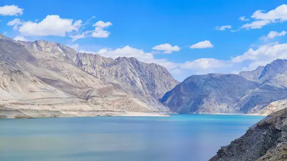 巍峨的群山沉睡在时光里，棱角分明的轮廓像是大地未完成的诗行。碧蓝的湖水静静流淌，将天空的碎片揉碎成柔软的波光。云朵慢悠悠地踱过山巅，仿佛怕惊扰了这片亘古的安宁。