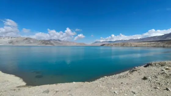 这汪碧蓝的湖水，是天空沉落在人间的一面镜子，静得能听见云朵飘过的叹息。远山沉默地守护着亘古的宁静，仿佛时间在这里凝成了琥珀。风掠过水面，荡开一圈圈细碎的银光，像是大地写给苍穹的密语。