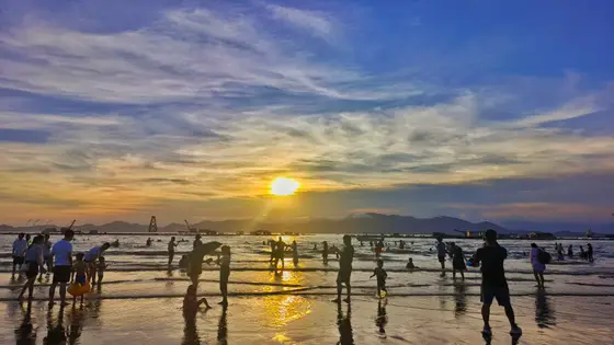 夕阳熔金坠海，将流光揉碎在浪尖。  
暗色剪影散落如星，踏着碎浪私语。  
远处山影朦胧，暮云低垂，与喧闹人声一同沉入  
这半明半暗的暮色深处。