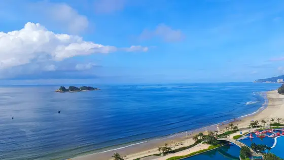 天空的蓝，是海的倒影；海的蓝，是天空的沉醉。浪花轻吻着沙滩，留下白色的诗句，而那座小岛，像一枚碧玉，静静卧在蓝绸之上。远处有舟，近处有影，人与浪，都在这无边的宁静里，轻轻呼吸。